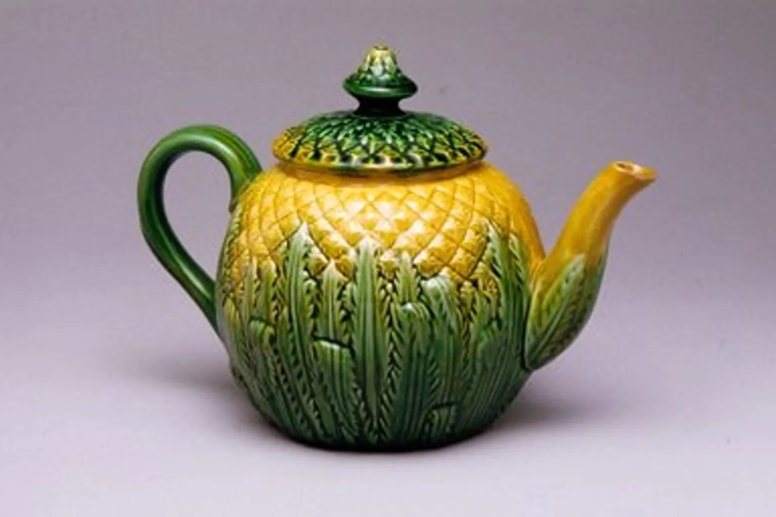Small photo of a yellow and green pineapple-shaped teapot, stretched 4× and blurry